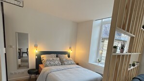 Une chambre à coucher avec un lit, des tables de chevet, une fenêtre et une vue sur l’extérieur.