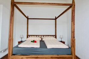 Cozy retreat with a four-poster bed, bedside tables, and a radiator.