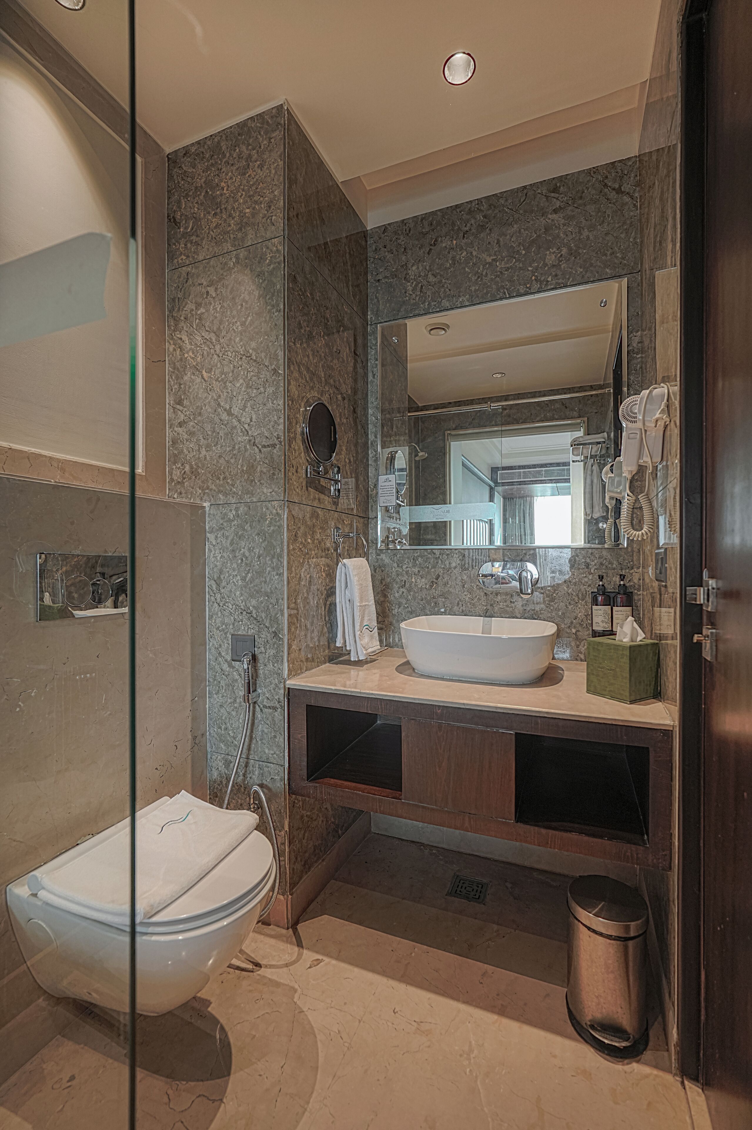A modern bathroom with a freestanding toilet, a sink with a mirror above, and a shower area.