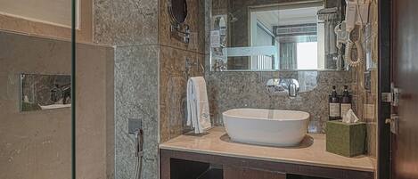 A modern bathroom with a freestanding toilet, a sink with a mirror above, and a shower area.