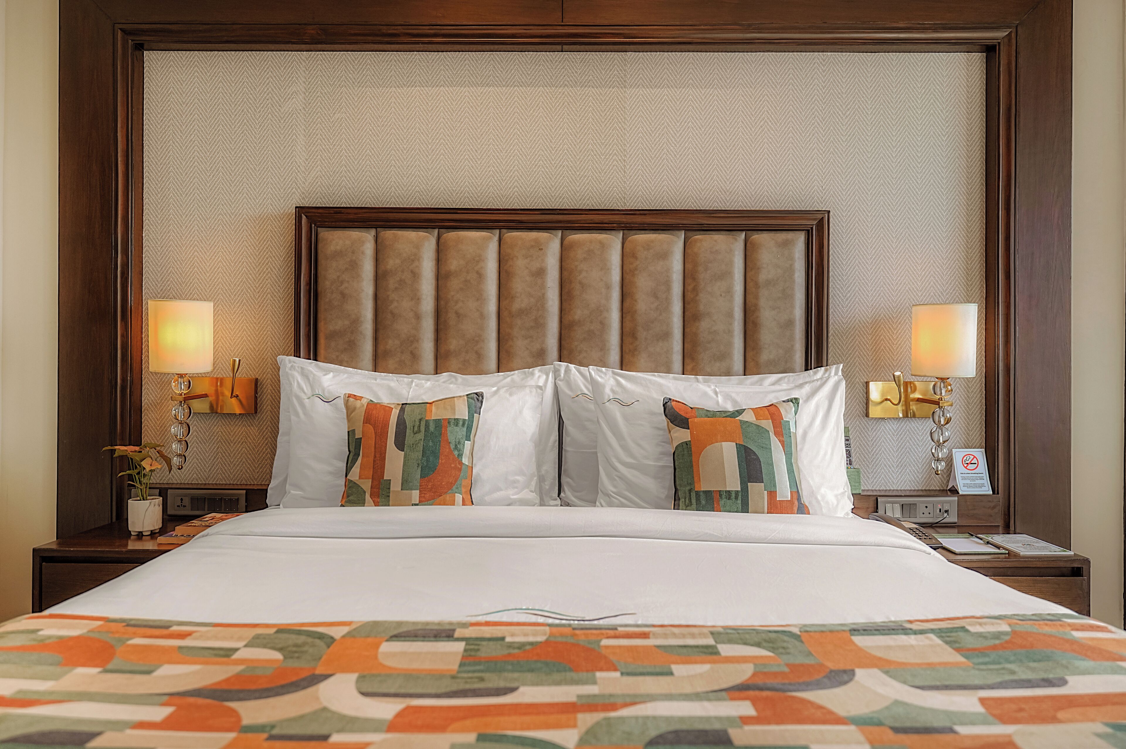 A hotel room with a large bed, two nightstands, a headboard, and two wall-mounted lamps.