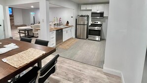A modern kitchen with white cabinets, stainless steel appliances, and a wooden dining table with chairs. - Super Spacious 3 Bedroom House, w/2 Living Rooms and Close to Everything  (Shreveport)