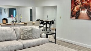 A modern living room with a sectional sofa, a coffee table, and a dining area with a table and chairs. - Super Spacious 3 Bedroom House, w/2 Living Rooms and Close to Everything  (Shreveport)
