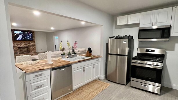 A modern kitchen with white cabinetry, stainless steel appliances, and a wooden countertop. - Super Spacious 3 Bedroom House, w/2 Living Rooms and Close to Everything  (Shreveport)