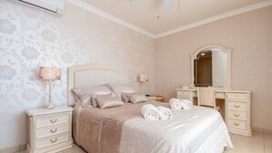 Un dormitorio ordenado con cama, mesitas de noche, cómoda y espejo.