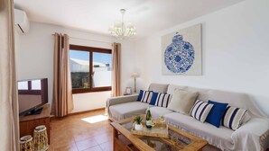 A living room with a sofa, TV, and a coffee table with drinks. - Villa Rioja - Three Bedroom Villa, Sleeps 6 (Playa Blanca)