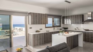 Una cocina moderna con una isla grande, armarios de madera y vistas al océano.