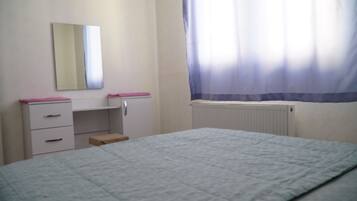 Un dormitorio con cama, cómoda, espejo y ventana con cortinas.