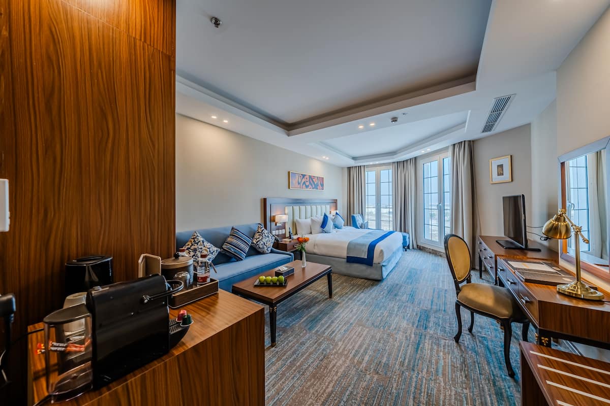 A hotel room with a bed, sofa, desk, and coffee machine.