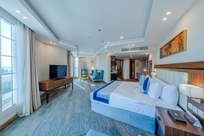 Ein Hotelzimmer mit einem großen Bett, einem Fernseher, einem Schreibtisch und einem Sessel.