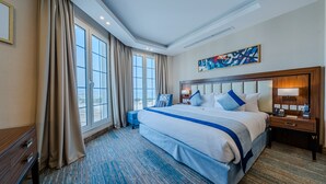 A hotel room with a large bed, a nightstand, a desk, and a window with curtains. - Braira Al Jubail (Al Jubail)