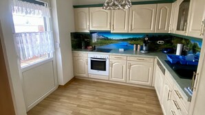 A kitchen with wooden flooring, white cabinets, a built-in oven, and a decorative backsplash.
