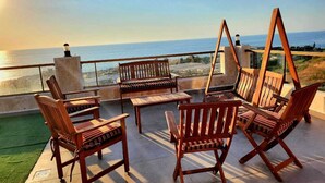 Une terrasse dotée de mobilier en bois et offrant une vue sur la mer.