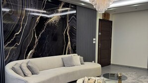 Un salon moderne avec un canapé aux lignes courbes, une table basse en marbre et un lustre.