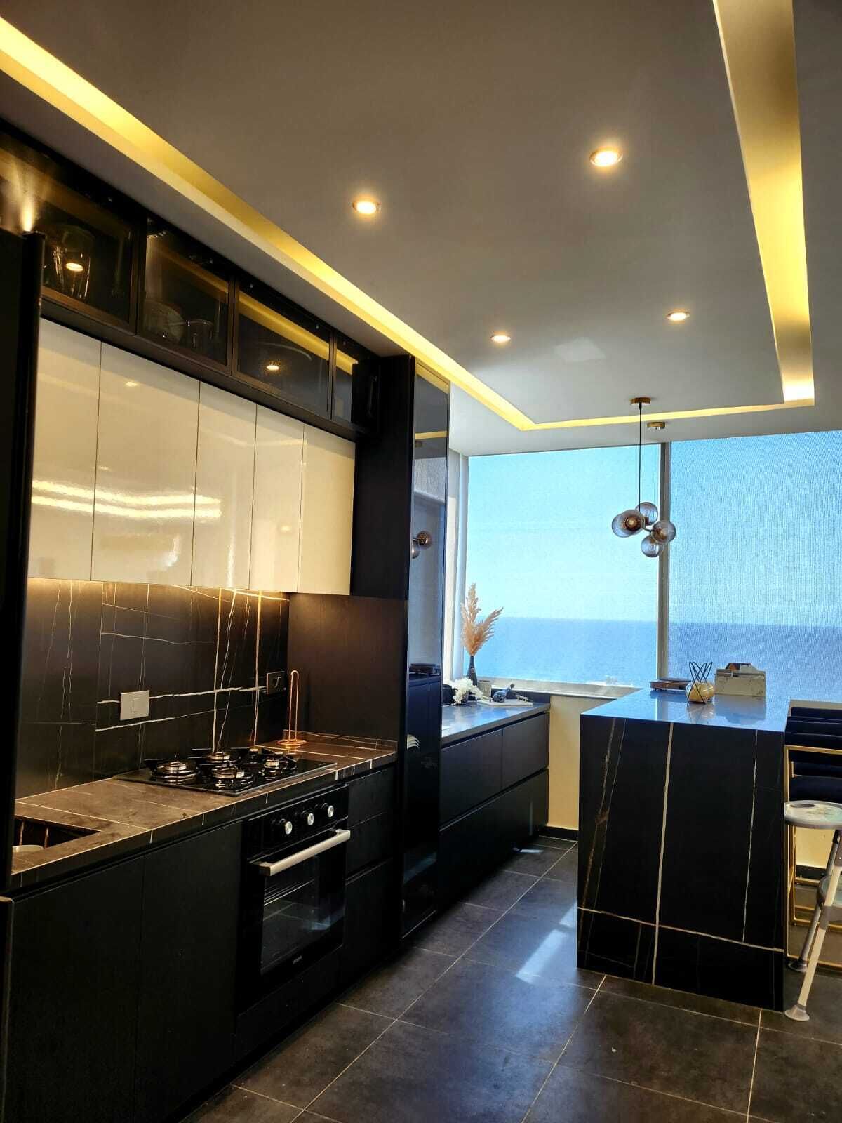 Een moderne keuken met een centraal eiland, geïntegreerde apparatuur en uitzicht op zee.