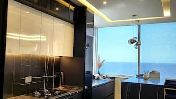 Een moderne keuken met een centraal eiland, geïntegreerde apparatuur en uitzicht op zee.