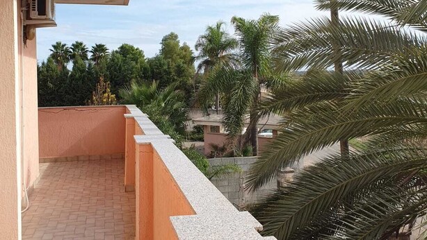 A balcony with a tiled floor and a low wall, overlooking a residential area with palm trees and houses. - Cozy, warm and in a strategic neighborhood (Nardò)