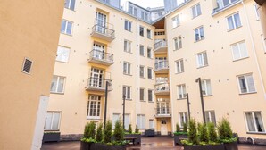 A multi-story residential building with balconies, a courtyard with planters, and a flat roof. - Spacious apt on Tranquil Courtyard (Helsinki)