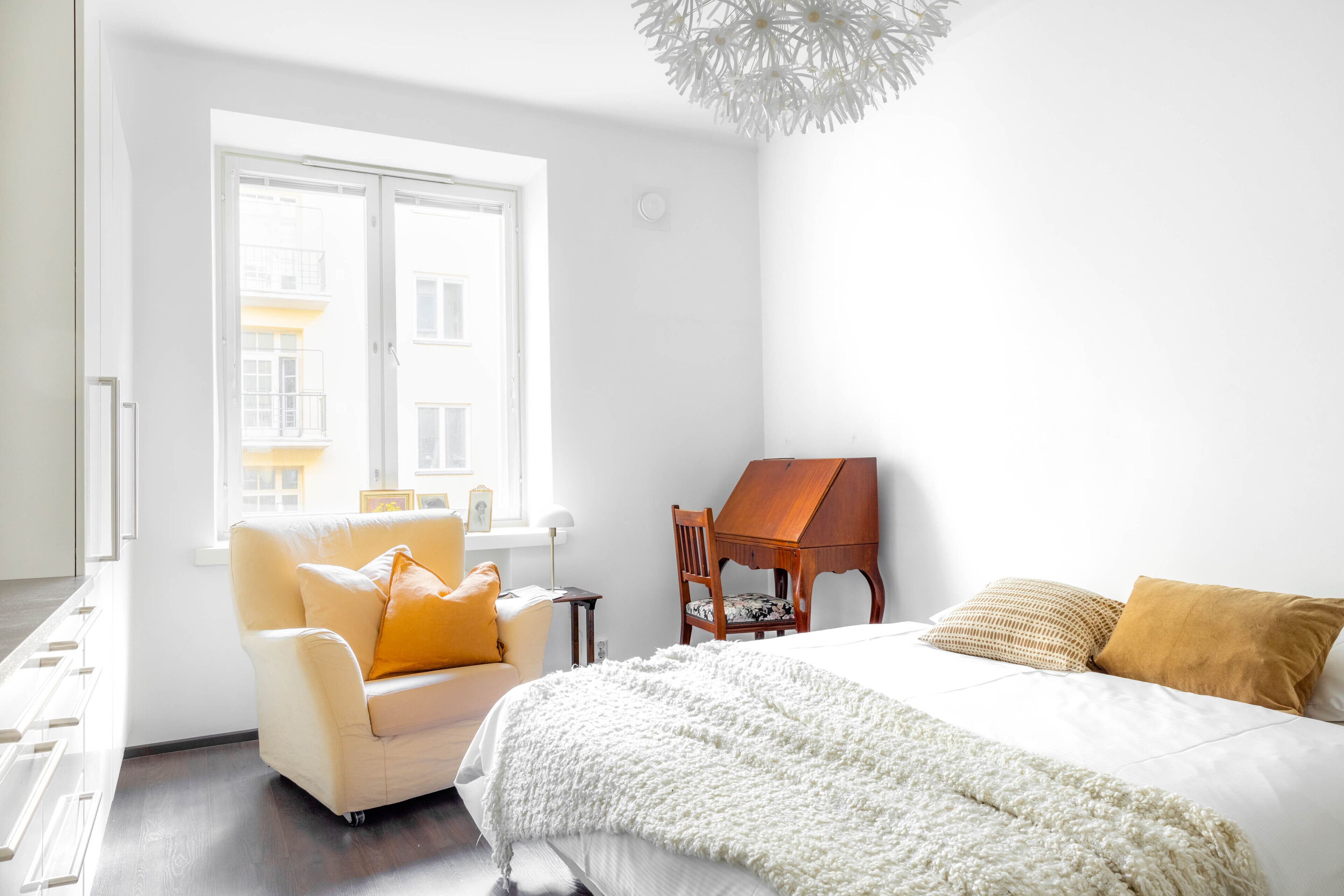 A bedroom with a bed, a chair, a desk, and a window.