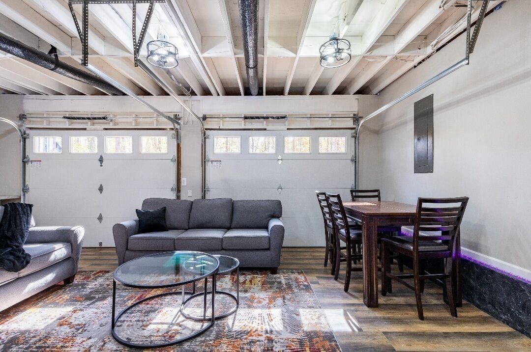 Une pièce spacieuse avec un canapé gris, une table basse en verre et une table à manger avec des chaises.
