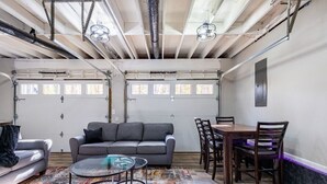 A spacious room with a gray sofa, a glass coffee table, and a dining table with chairs. - The Blissful Hideaway w/ large backyard, jacuzzi and two connecting decks (Villa Rica)