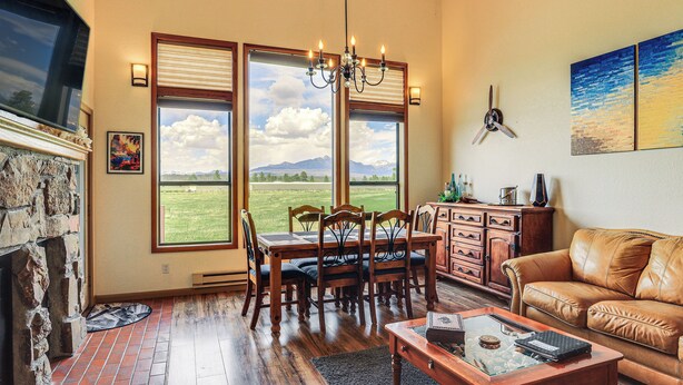 A dining area with a view of mountains, a fireplace, and a leather couch.