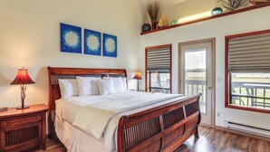 A bedroom with a wooden bed, two bedside lamps, and a view of the outdoors through a door.
