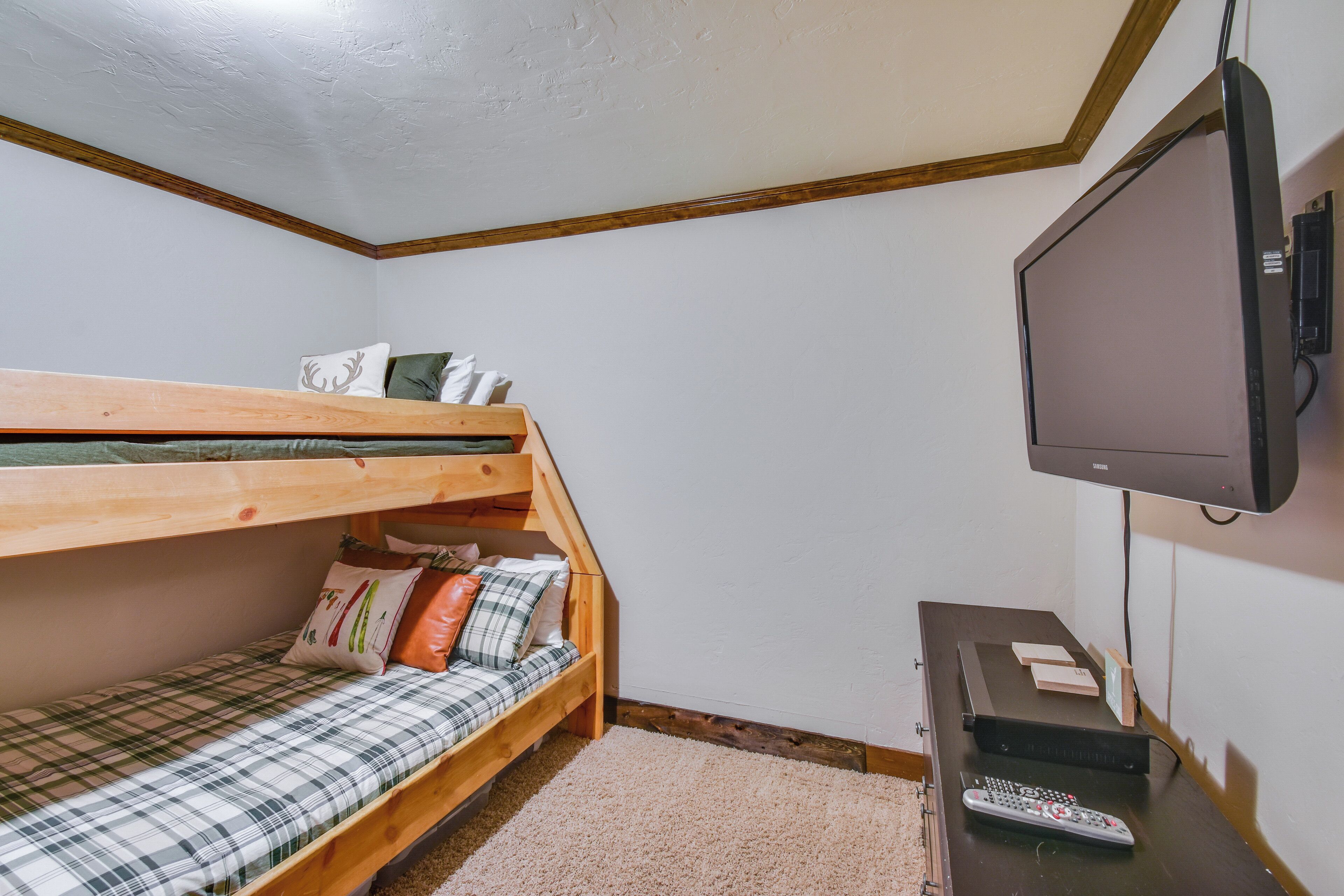 A small room with a bunk bed, a television, and a remote control on a table.