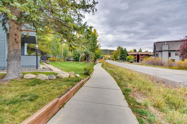 A residential street with houses, a sidewalk, and trees.