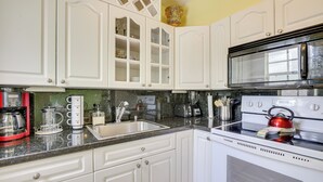 A kitchen with white cabinets, a stainless steel sink, a red kettle, and a microwave. - 4 Mi to Beach: Hollywood Home w/ Patios! (Hollywood)