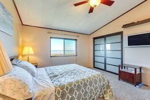 A bedroom with a bed, a window, a ceiling fan, and a TV mounted on the wall. - Oceanfront Port Angeles Home w/ Yard & Views! (Port Angeles)