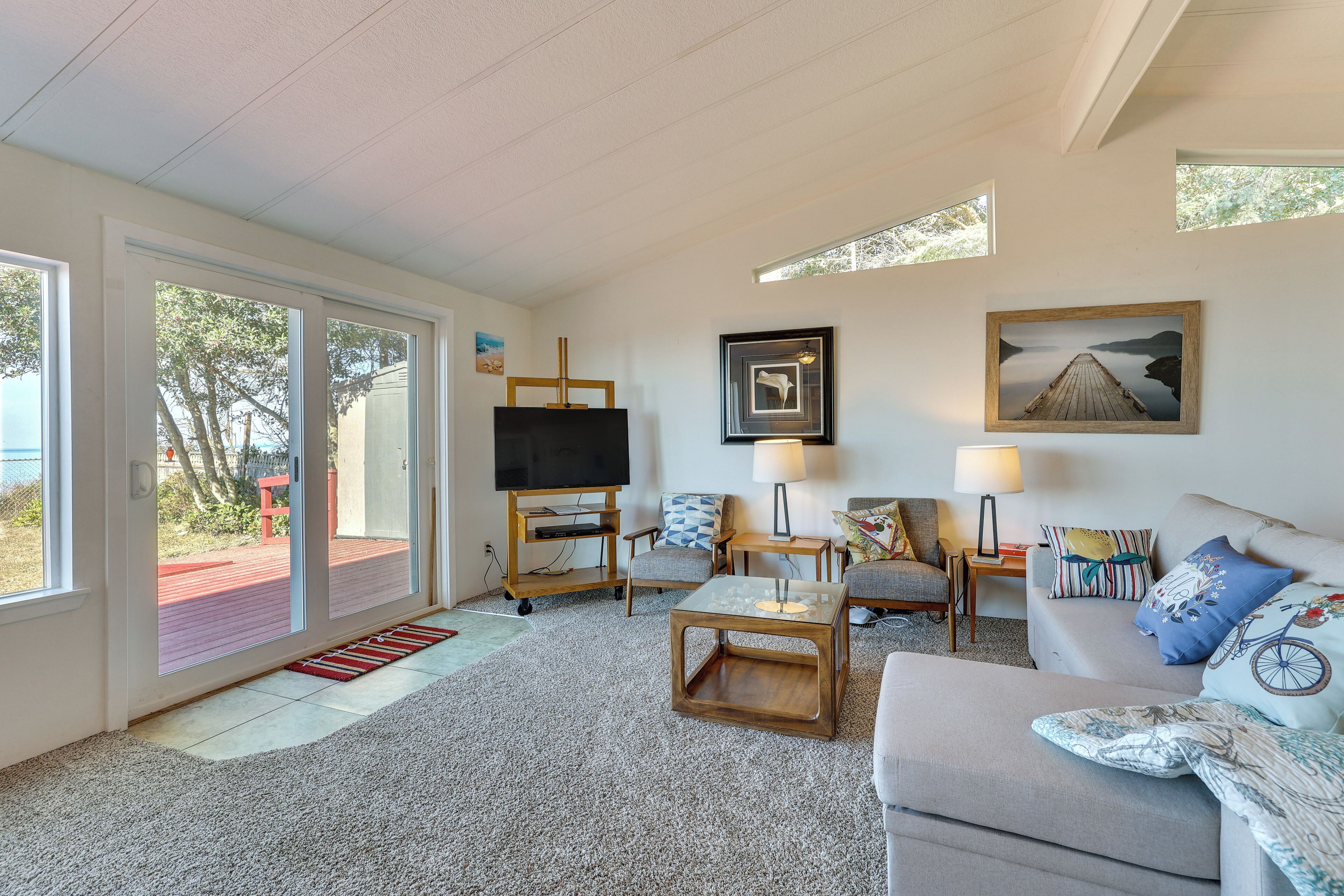 A spacious living room with a large TV, comfortable seating, and artwork on the walls.