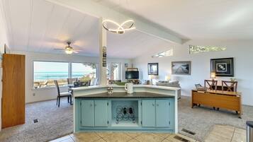 A spacious kitchen with a large island, a ceiling fan, and a view of the ocean.