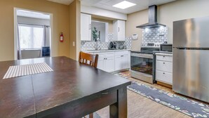 A kitchen with white cabinets, a stainless steel range hood, and a refrigerator.