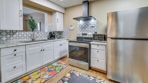 A modern kitchen with white cabinets, stainless steel appliances, and a patterned backsplash.