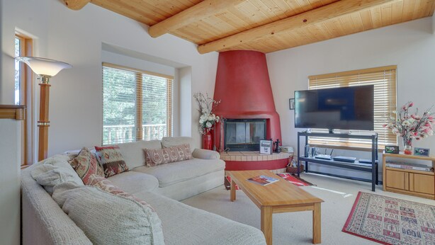 Een woonkamer met een modulaire bank, een open haard, een televisie en een houten plafond.
