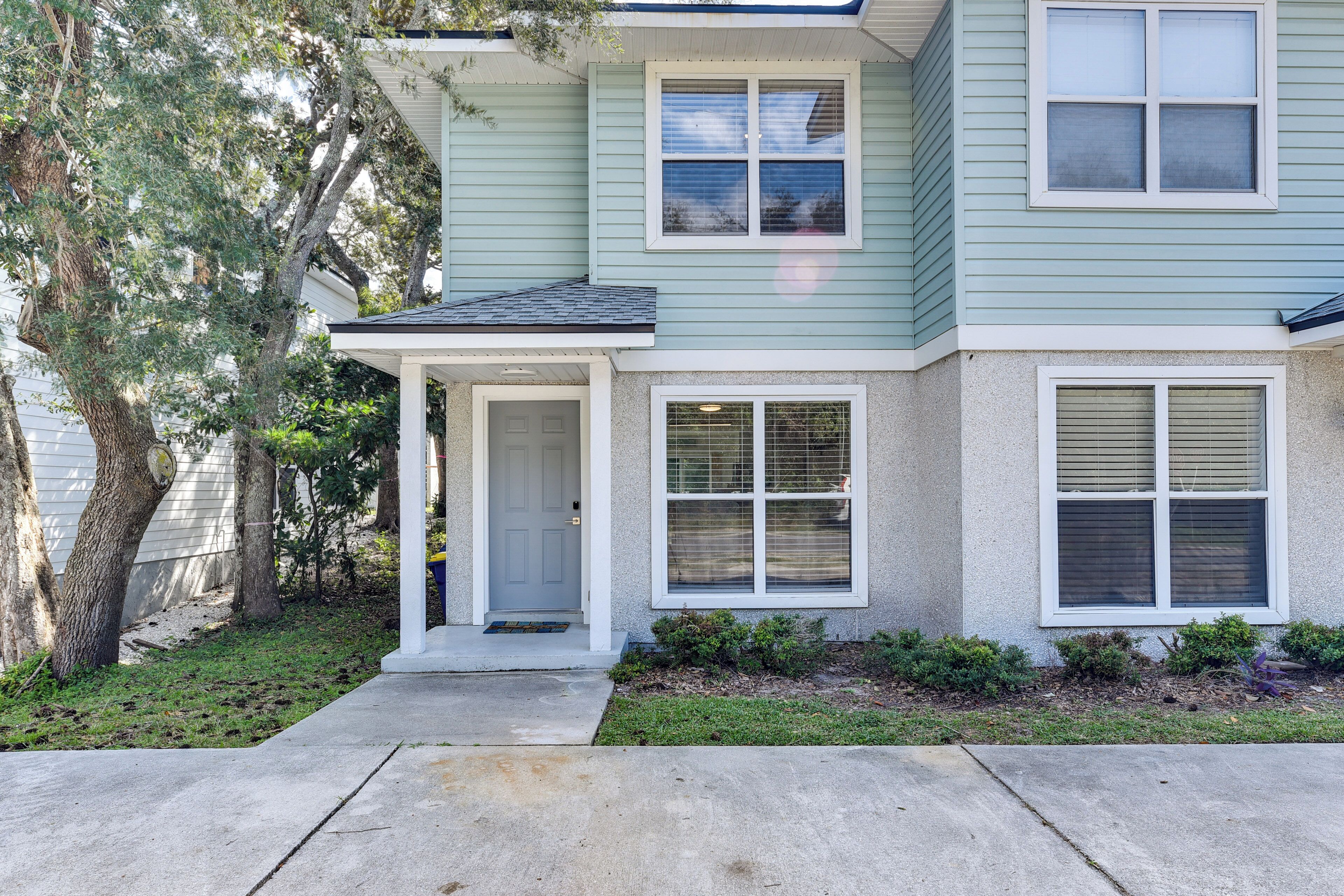 A two-story house with a front porch, a door, and two windows with shutters.