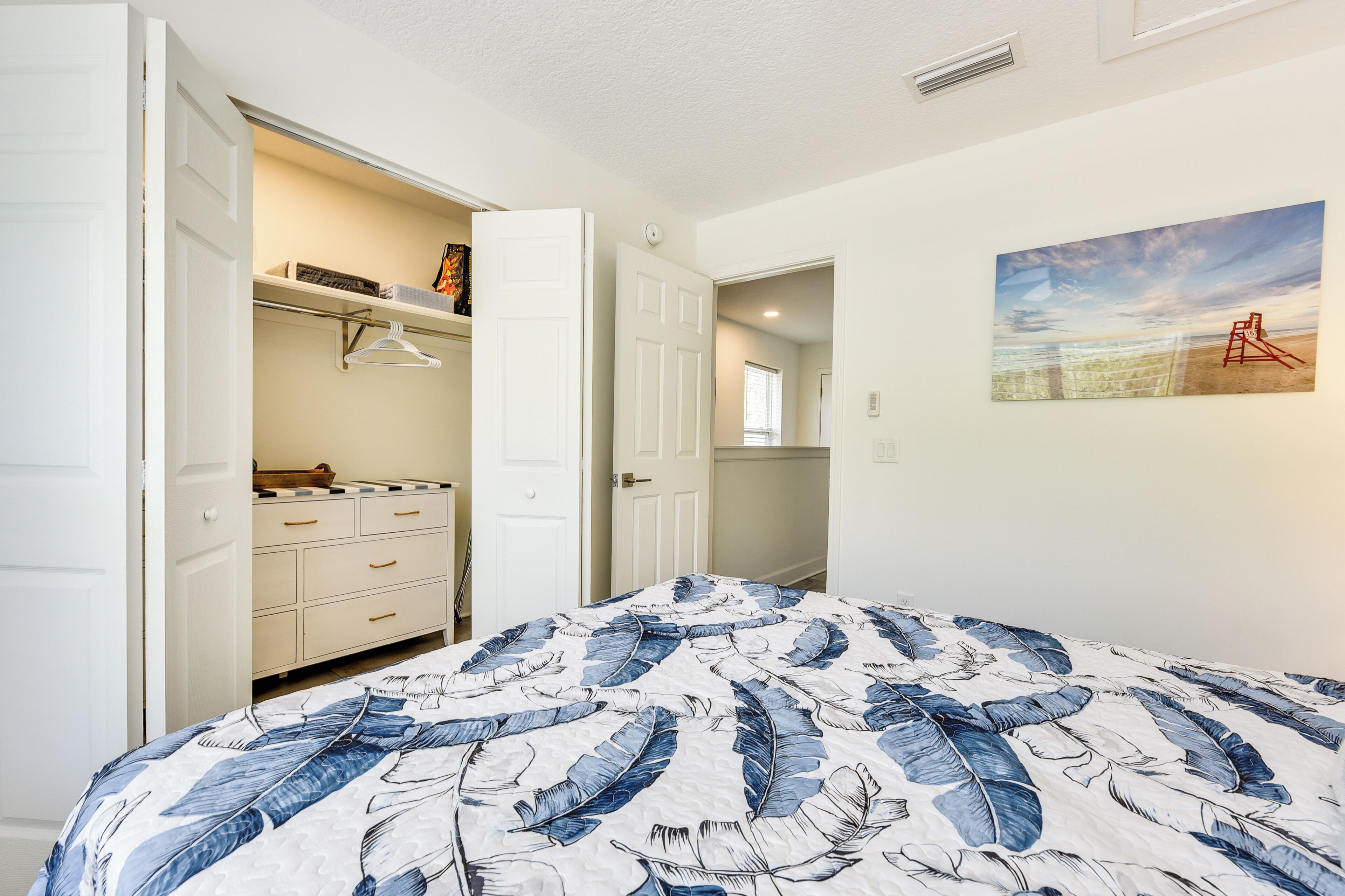 Un dormitorio con una cama, un armario y un cuadro en la pared.
