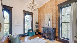A spacious living room with a leather sofa, a white rug, a brick wall, and a fireplace. - Chic & Historic Apartment ~ 6 Mi to Louisville! (New Albany)