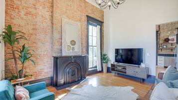 A living room with a brick wall, a fireplace, a television, and a sofa.