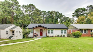 A residential property with a front lawn, a red door, and a brick house. - Updated Atlanta Home ~ 5 Mi to Downtown! (Atlanta)