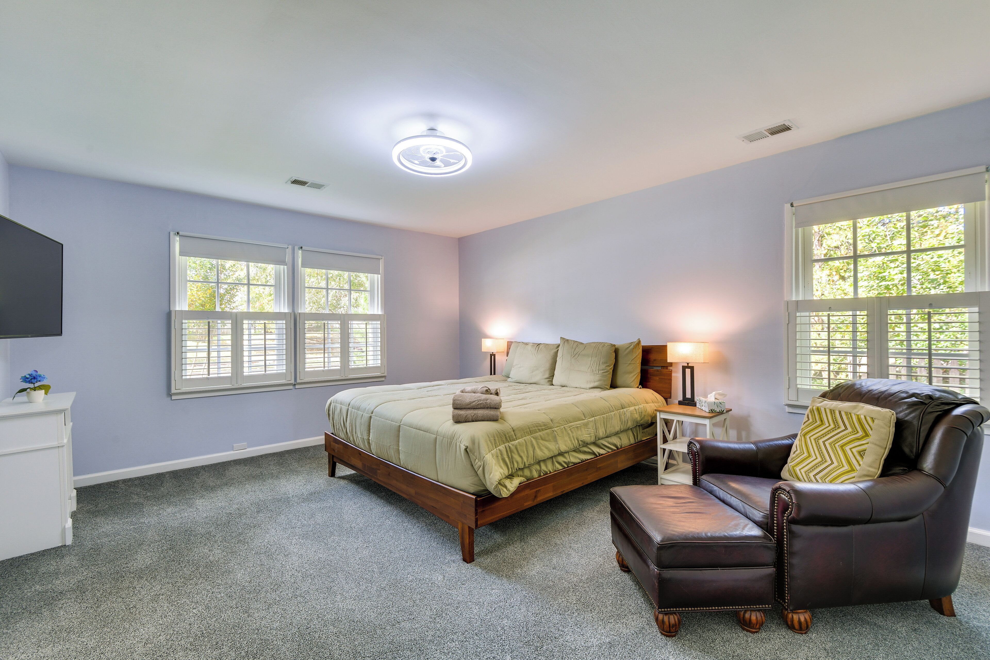 A bedroom with a bed, a chair, a nightstand, and a lamp.