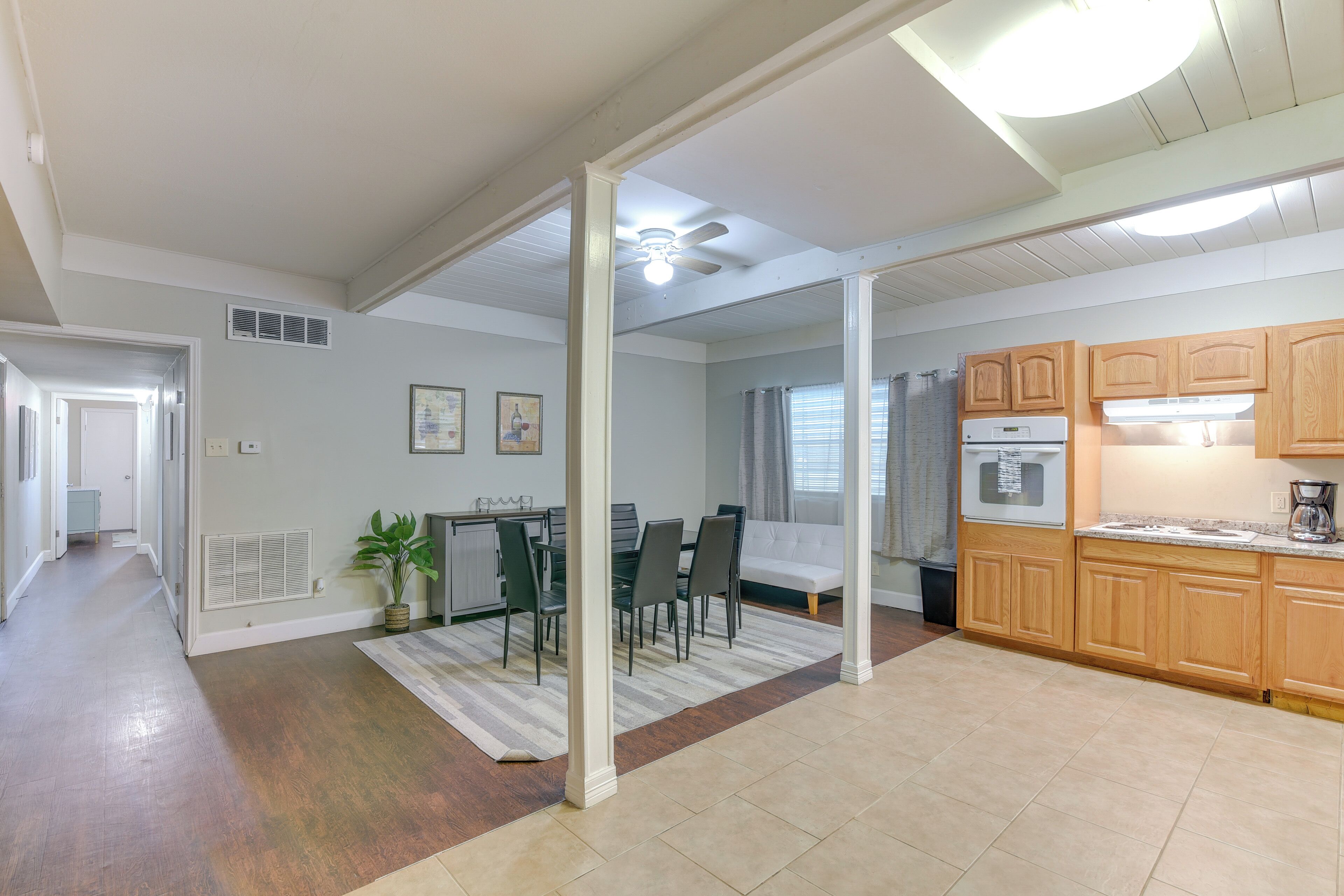 A modern kitchen with wooden cabinets, a built-in oven, and a dining area with a table and chairs.