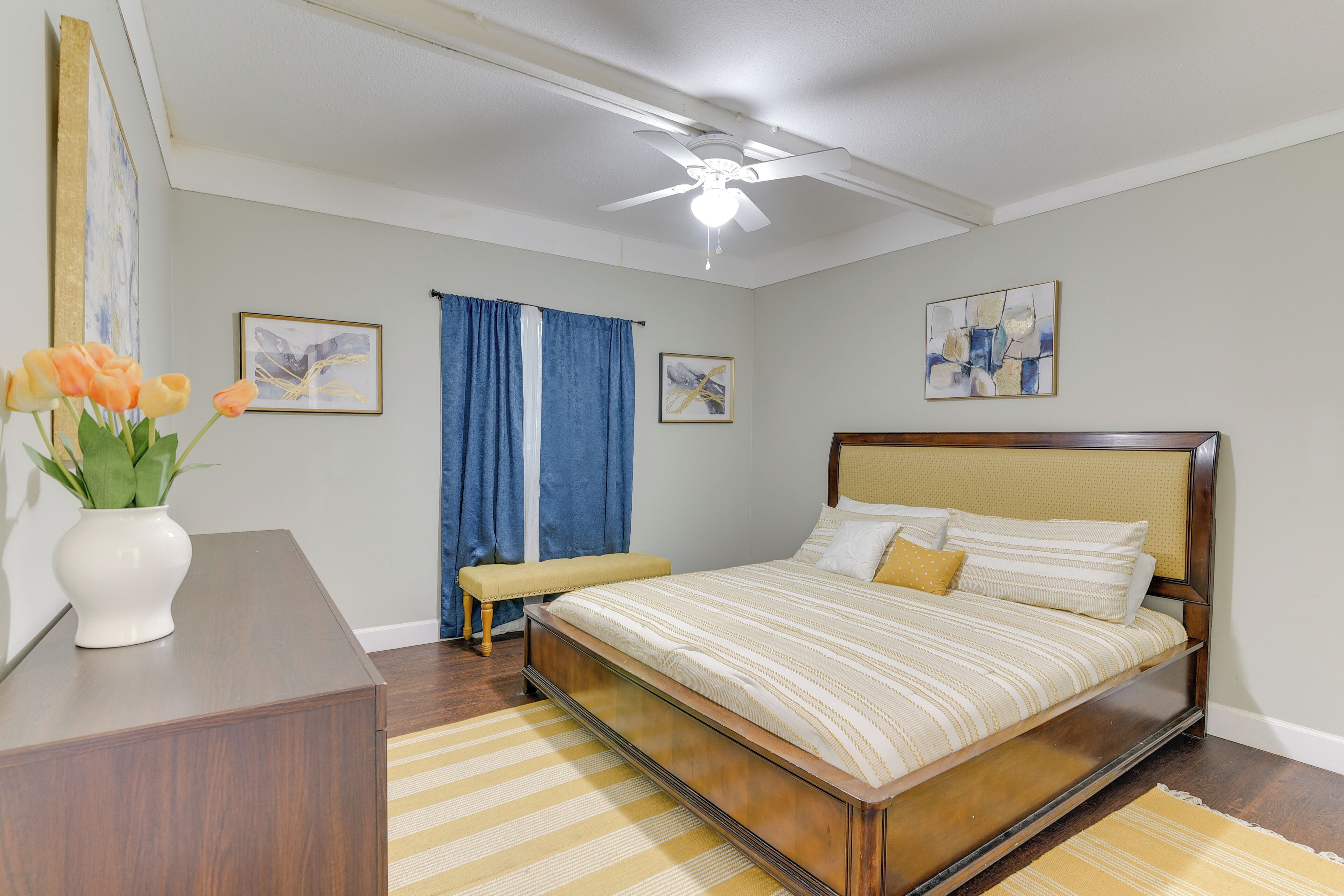 A bedroom with a bed, a bedside table, a bench, and a ceiling fan.