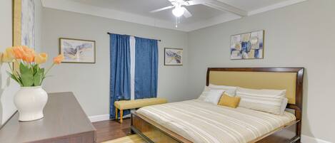 A bedroom with a bed, a bedside table, a bench, and a ceiling fan.