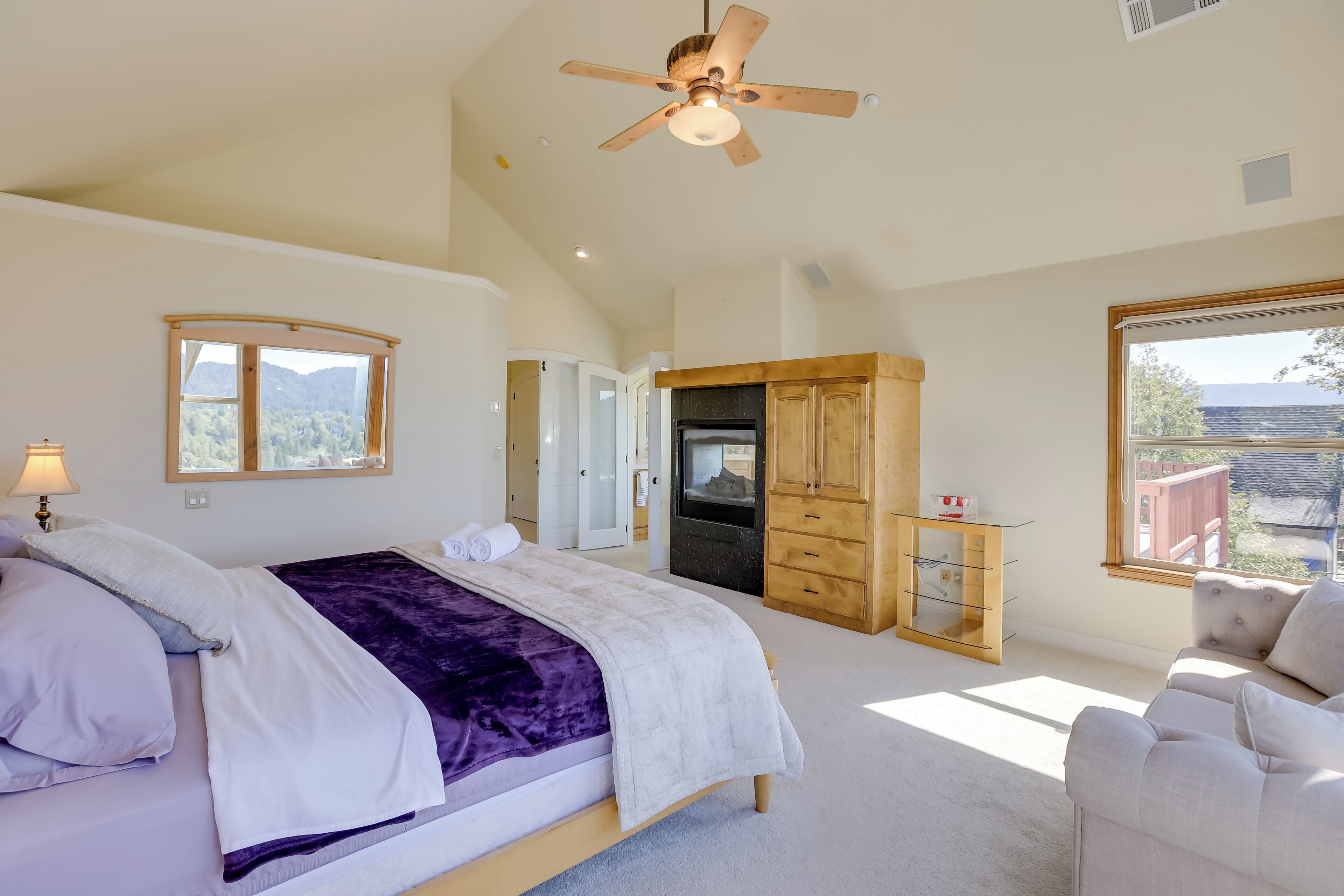 A bedroom with a bed, a ceiling fan, a wardrobe, and a window with a view of the outdoors.