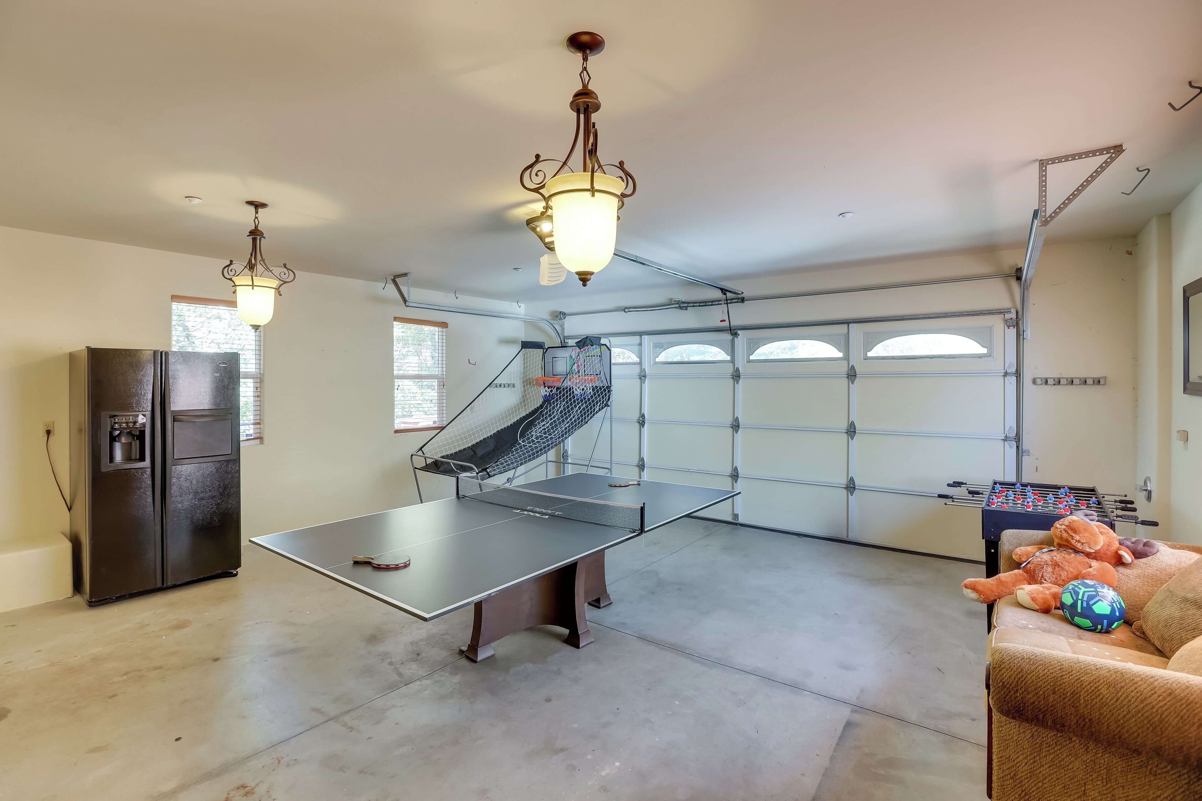 Ett rymligt garage med ett bordtennisbord, ett fotbollsspel och ett kylskåp.