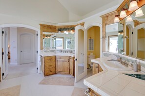 A spacious bathroom with a large vanity, multiple sinks, and a large mirror.