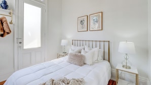Una camera da letto ordinata con un letto grande, comodini, una porta e due quadri appesi al muro.