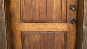Una puerta de madera con un emblema de cruz roja, una mirilla y un picaporte.
